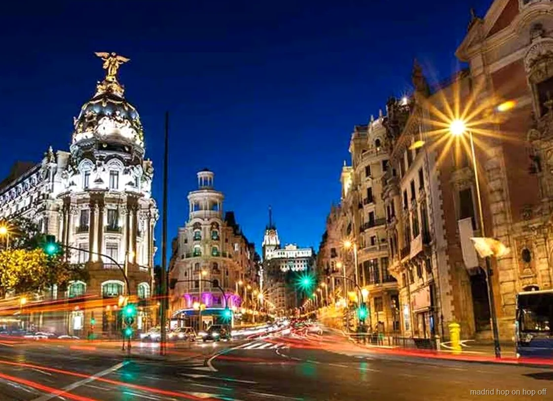 Bus del tour notturno hop-on hop-off di Madrid che passa davanti a monumenti illuminati