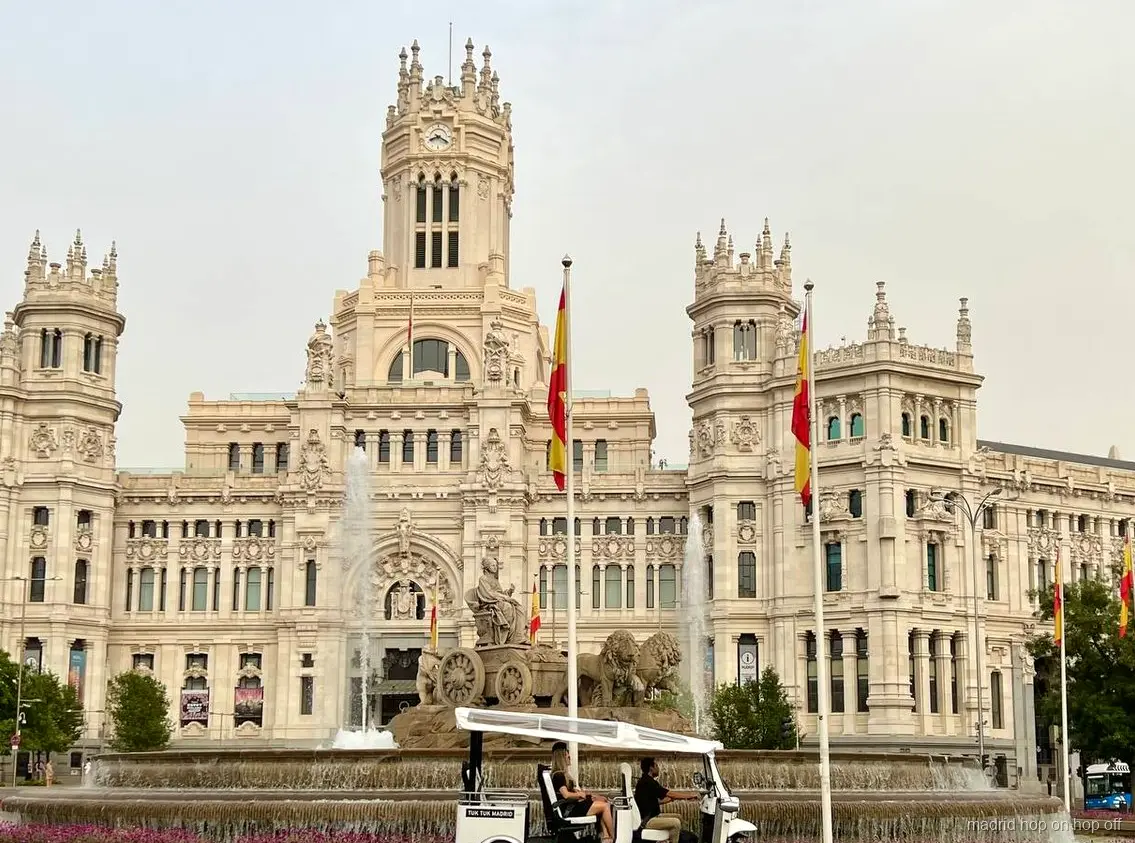 Guía bilingüe conduciendo un tuk tuk eléctrico por Madrid